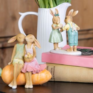 Two colorful decorative Easter bunny figurines each depict two Easter bunnies in a loving setting.