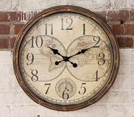 The photo depicts an elegant mantel clock with a vintage appearance. The clock features a classic face against a white background. The clock face is surrounded by an elaborately decorated frame with swirling, baroque motifs. The frame has a weathered, white color that adds to its antique character. The clock is placed on what appears to be a windowsill, with sunlight streaming through a window with a weathered frame. This gives the scene a warm, inviting atmosphere and accentuates the texture of the clock's metal frame.