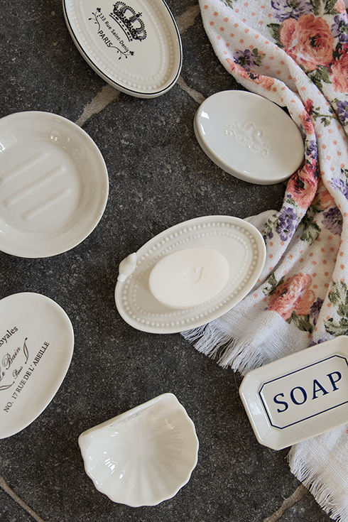Divers porte-savons en céramique recouverts d'une serviette d'invité ornée de pivoines roses