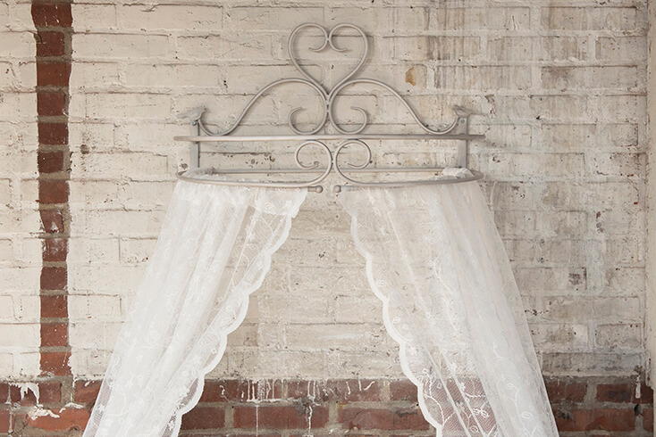 A bed canopy with a white lace curtain hanging from it