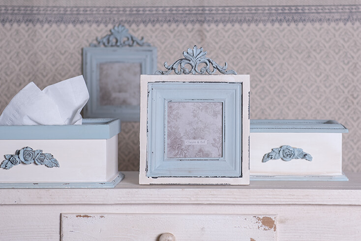 Due scatole per fazzoletti bianche e blu con cornici per foto dello stesso stile e colore