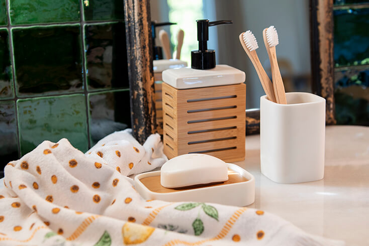 Un distributeur de savon brun, un porte-brosse à dents blanc, une porte-savon et un miroir