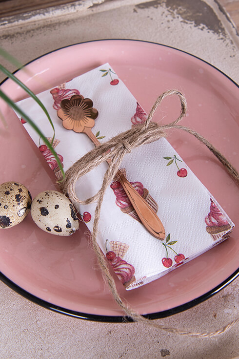 Une assiette rose, une serviette et une cuillère dorée