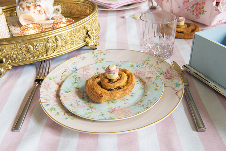 Pink plate with a light blue plate and a cinnamon roll