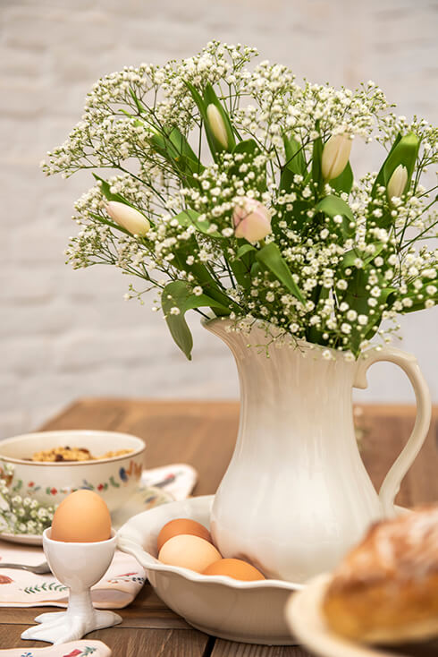 Una brocca con un bouquet e portauova in ceramica bianca