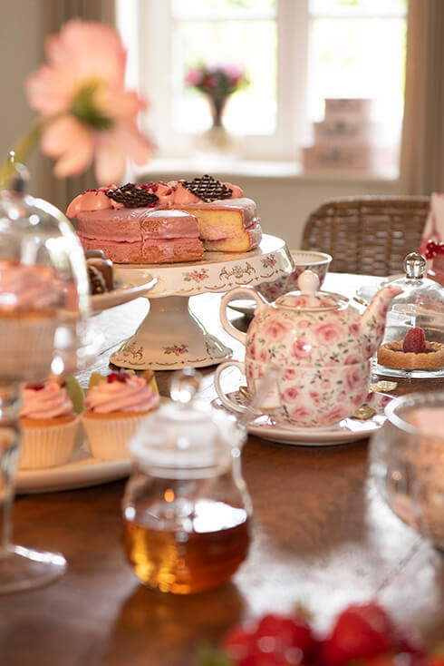 Een high tea tafel met een tea for one set en een taartplateau met gebak