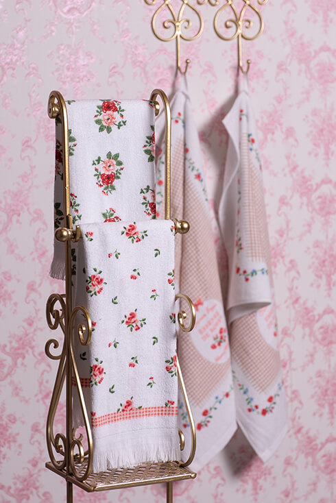 Un porta asciugamani dorato con asciugamani per gli ospiti con rose romantiche