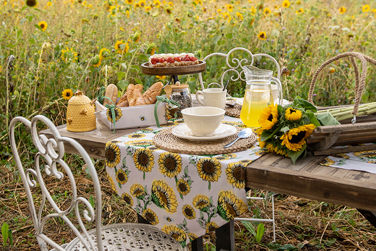 Holztisch mit Geschirr und einem Sonnenblumen-Tischdecke