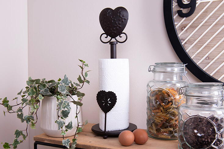 A black metal kitchen roll holder with a heart