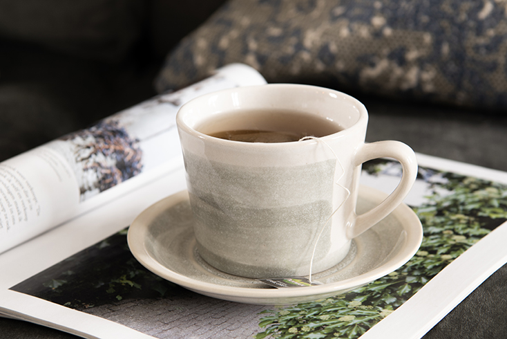 Keramieken kop en schotel in grijstinten en thee