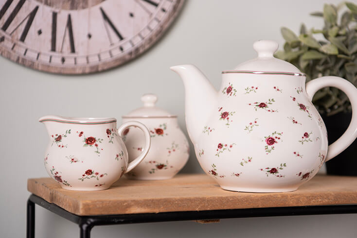 A white milk jug and sugar bowl with red roses and a white teapot with red roses