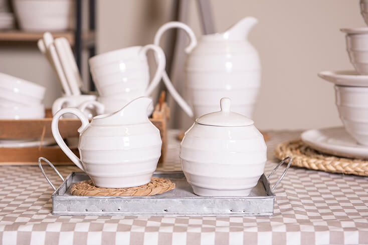 A metal tray with a white milk jug and sugar bowl