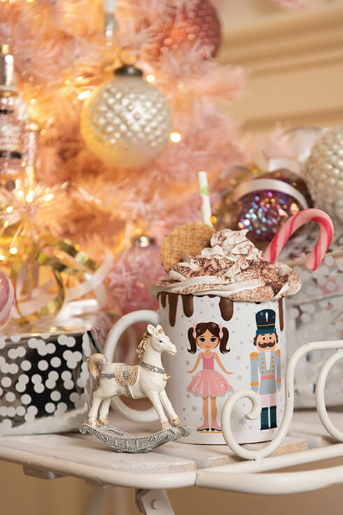 Une tasse avec un motif de Noël remplie de crème, accompagnée d'un cheval à bascule