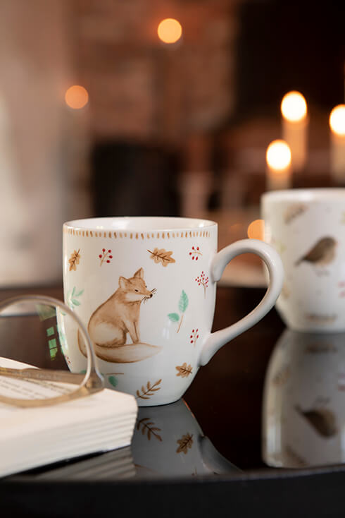 A white mug with a fox and autumn leaves