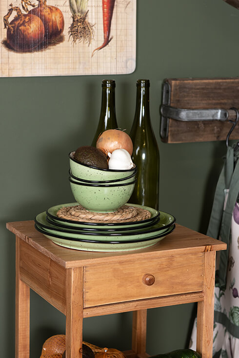 Des bols et des assiettes en céramique vertes posés sur des dessous de verre en osier