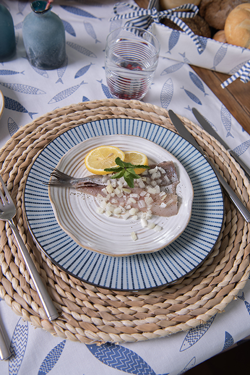 Set table with pickled fish with onions and a lemon