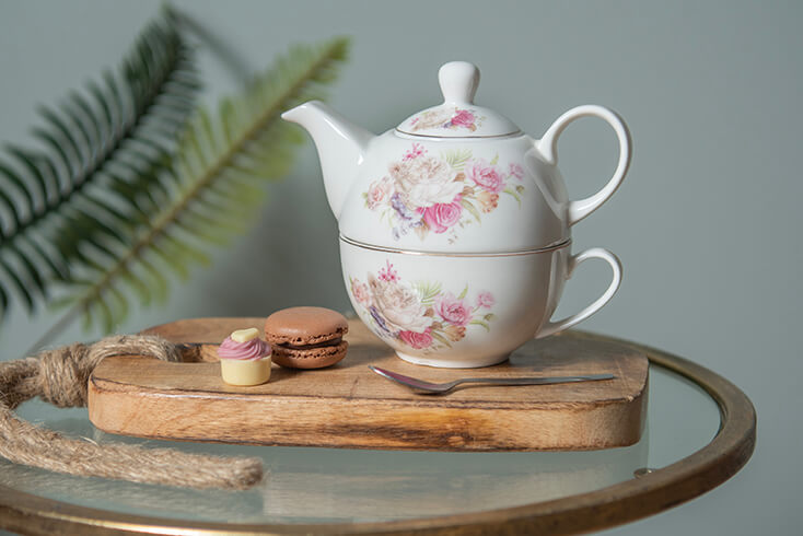 Een houten broodplank met een vintage tea for one set met gebakjes