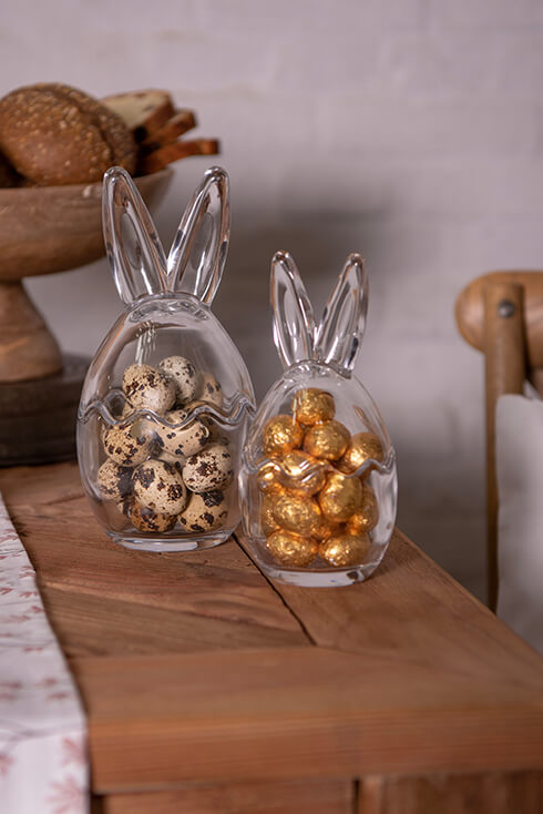 Deux bocaux en verre avec des oreilles de lapin remplis d'œufs de caille et de chocolats