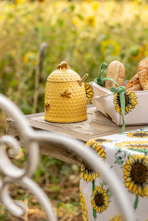 Un pot de miel en céramique jaune avec des rayures de miel et des abeilles