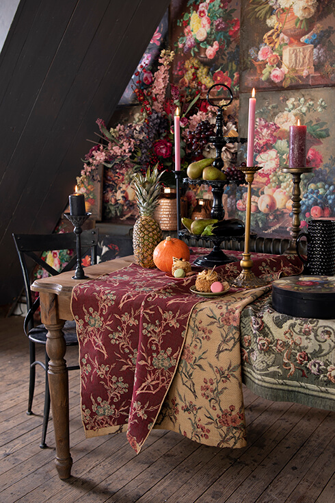 Une table de salle à manger baroque avec une étagère noire, des chandeliers, des fruits et une chaise de salle à manger noire