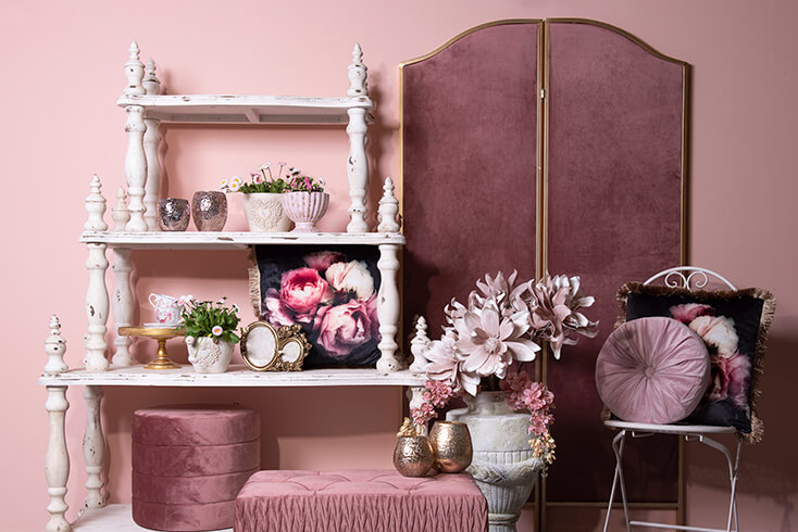 Une étagère de livre blanche campagnarde avec des accessoires de maison et à côté, un paravent rose