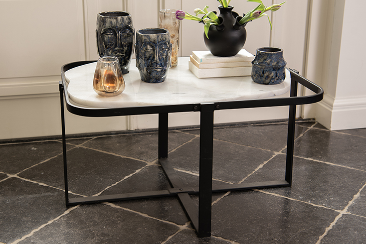 Une table basse en marbre avec des pots de fleurs bleus et des vases marron
