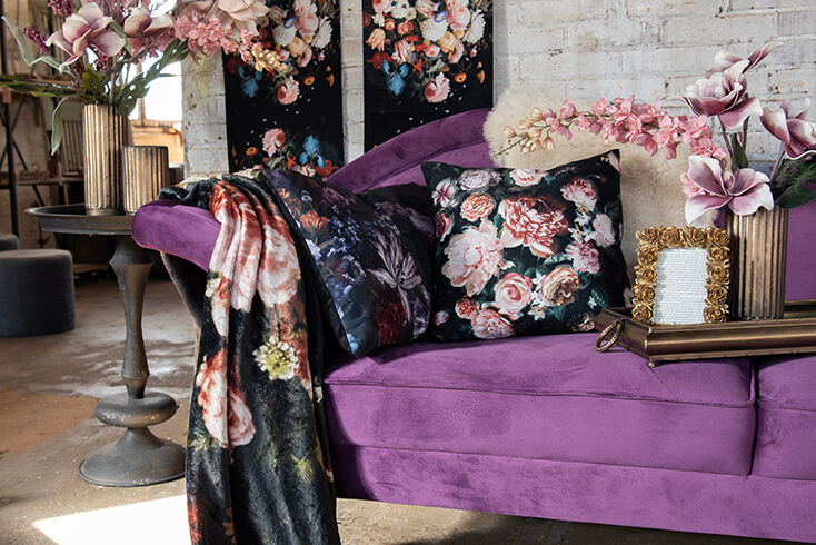 Ein lila Sofa mit zwei Kissen und einer Decke