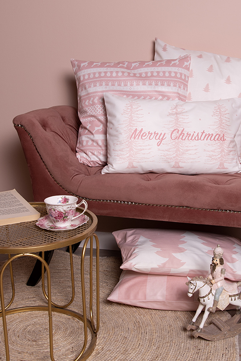 Un canapé rose avec trois coussins de Noël