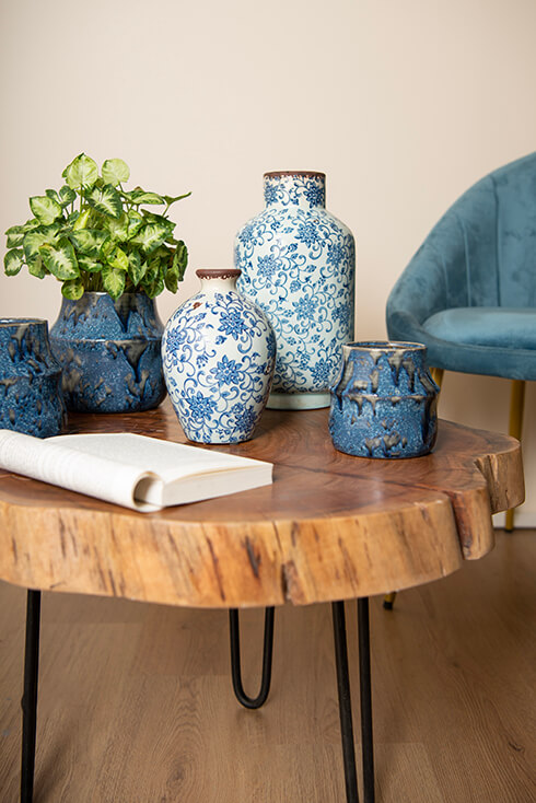 A wooden coffee table with blue flower pots and vases