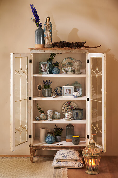 Una vetrina vintage riempita con oggetti d'arredamento per la casa, come vasi per fiori, vasi, stoviglie, cornici per foto e sculture decorative