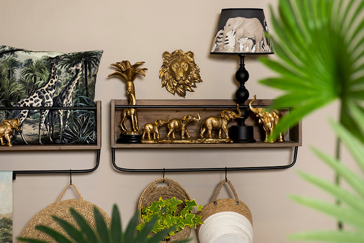 Una mensola da parete in legno con una lampada da tavolo e figurine di elefanti e giraffe