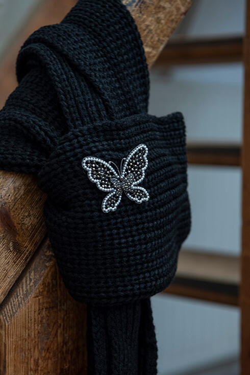 A black winter scarf with a butterfly brooch pinned on it