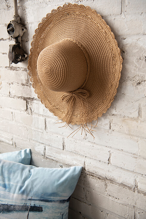 Un mur de briques blanches avec un chapeau de paille suspendu