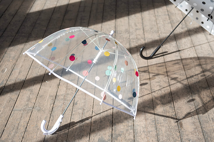 Een transparante kinderparaplu met gekleurde stippen