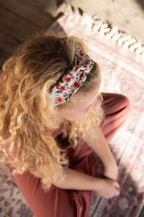 Een meid die een haarband draagt met rode bloemetjes