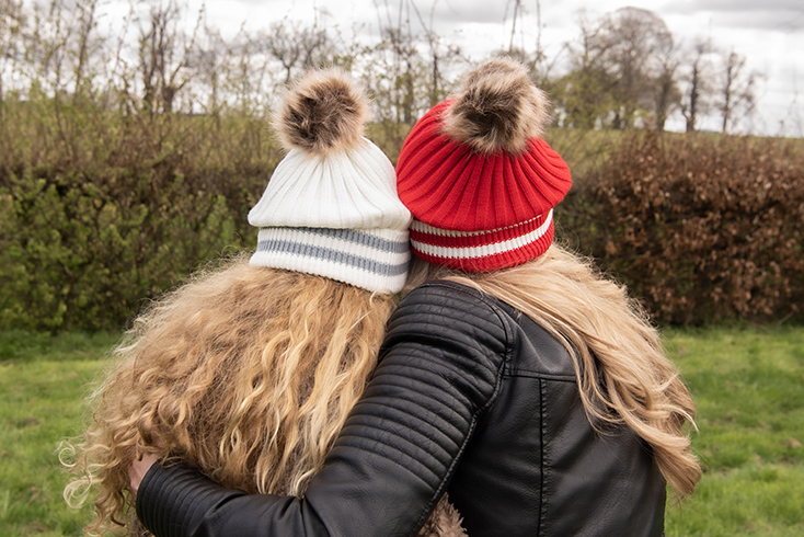 Madre e figlia indossano entrambe cappelli invernali bianchi e rossi