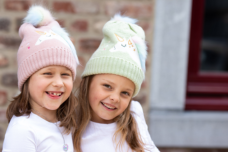 Due ragazze indossano un cappello per bambini con un unicorno in rosa e verde