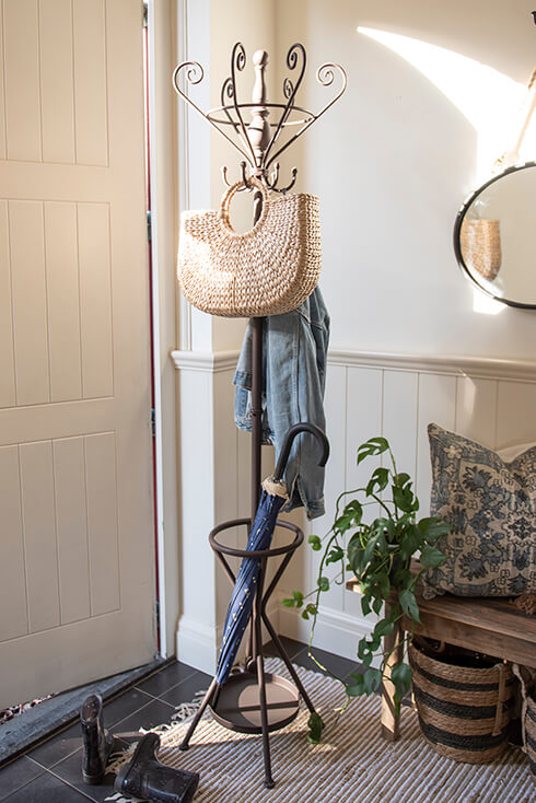 A coat rack with an umbrella on which a denim jacket and bag hang