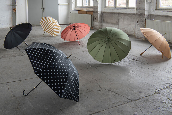 A collection of open umbrellas in colors such as green, pink, yellow, blue and beige