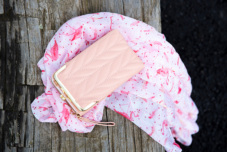 A pink summer scarf with a flamingo on it and a light pink wallet