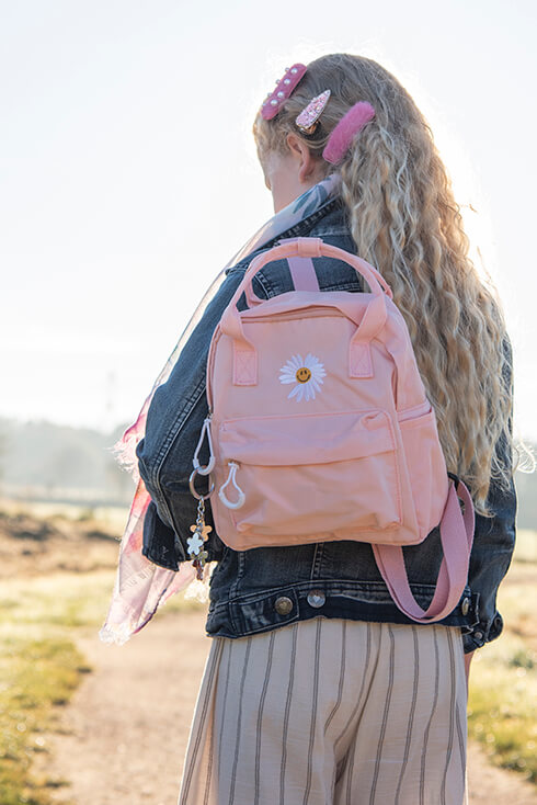 Une fille portant un sac à dos rose avec une marguerite