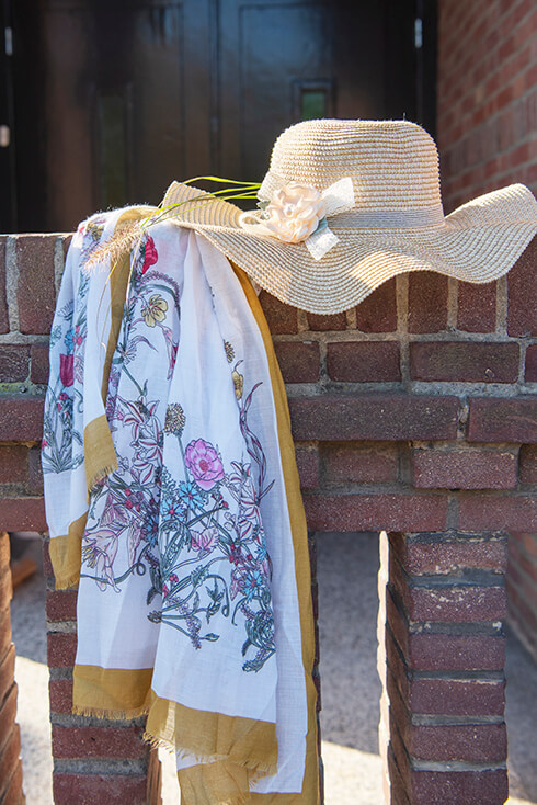 A floral summer scarf with a beige sun hat featuring a pink flower