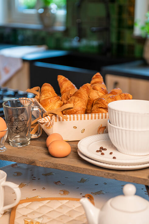 Beige bread basket with coffee beans and coffee, filled with croissants