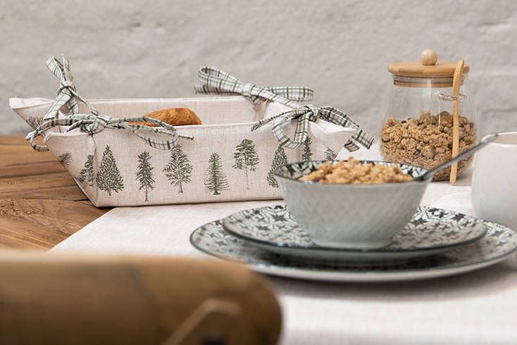 Un tavolo da pranzo rustico con un cestino del pane in lino con alberi verdi