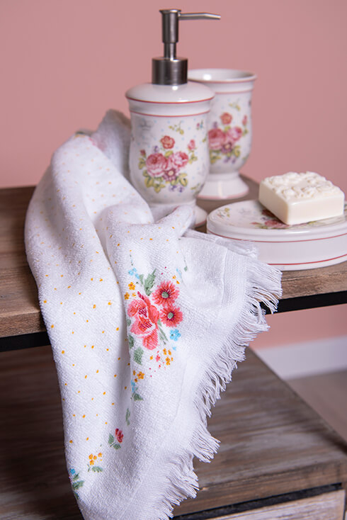 Un dispenser di sapone romantico e porta sapone con un asciugamano per gli ospiti a tema floreale