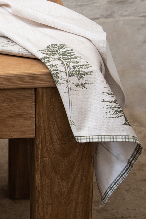 A linen tea towel with green pine trees