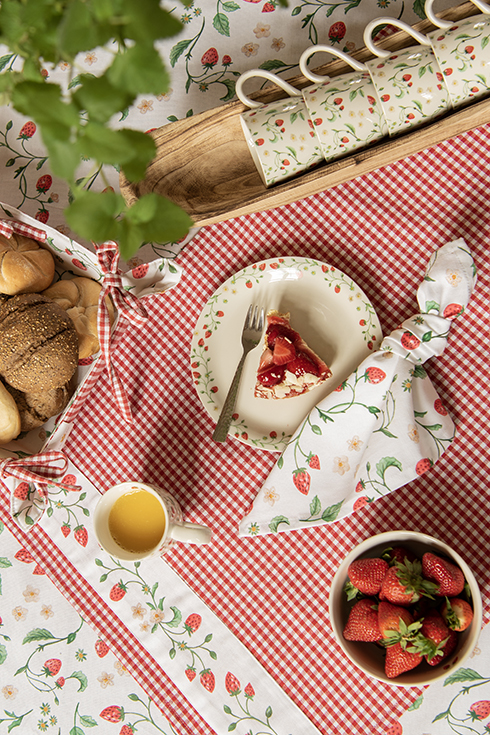 A strawberry-themed set with a tablecloth, breadbasket, napkin, and strawberry-patterned tableware