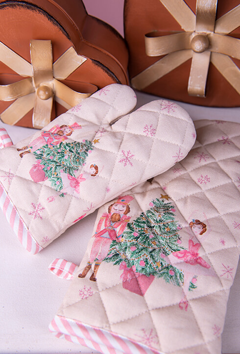 A pink children's oven mitt with a Christmas tree, nutcracker, and ballerina