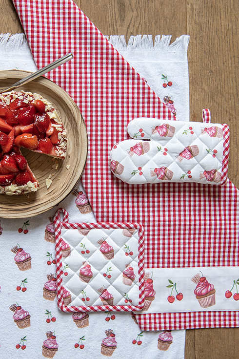 A children's oven mitt and children's pot holder with cupcakes and a strawberry cake on a wooden platter