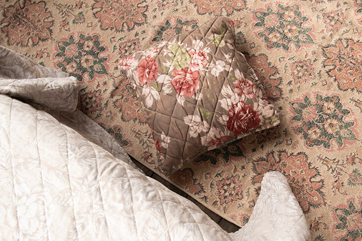 A brown cushion cover with pink peonies filled with cushioning